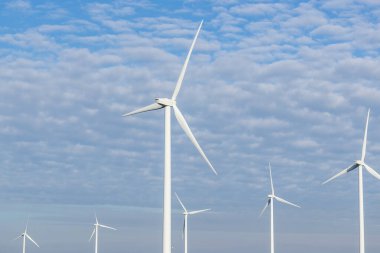 several wind turbines with cloudy blue sky