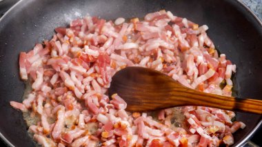 pork lardons cooked in a frying pan close-up