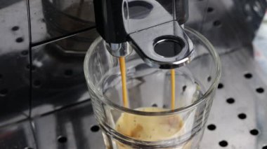 Kahve makinası bir fincan kahve dolduruyor.