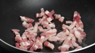 pork lardons cooked in a frying pan close-up