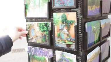 Askıdaki kartpostallara bakan kişi.,