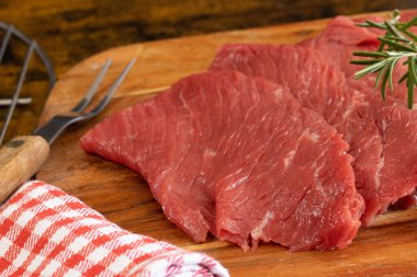 Birkaç çiğ biftek, yakın plan, kesim tahtasının üzerinde.