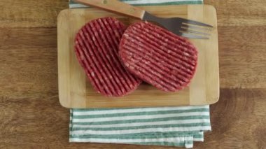 Tahtadaki çiğ sığır eti burgerlerini kapatın.