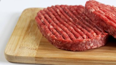 Tahtadaki çiğ sığır eti burgerlerini kapatın.