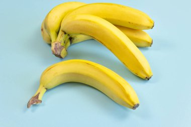 Birkaç muz, yakın plan, mavi arka planda izole edilmiş.