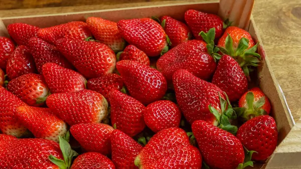 Stock image box of strawberries, close-up, on a wooden table