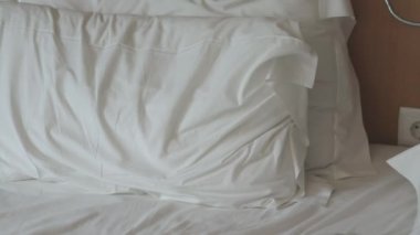 Beyaz çarşaflı yapılmamış yatak. Yapılmamış boş yatak. Bir gece uyuduktan sonra otel odasında yapılmamış bir yatak çarşafının yakın çekimi..