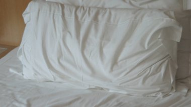 Beyaz çarşaflı yapılmamış yatak. Yapılmamış boş yatak. Bir gece uyuduktan sonra otel odasında yapılmamış bir yatak çarşafının yakın çekimi..