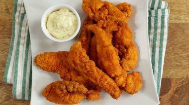 Kızarmış tavuk parçaları ve bir tabakta sos.