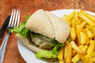 Bir tabak hamburger ve patates kızartması yakın.