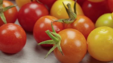 Farklı renklerde birkaç kiraz domatesi, yakın plan, bir masanın üzerinde.