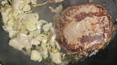 Tavada kıymalı biftek ve arpacık soğanı şeritleri pişirmek.
