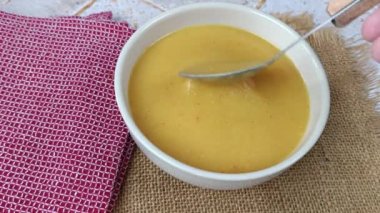 Kase içinde sebze çorbası, yemek kaşığıyla karıştırılmış.