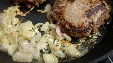 Tavada kıymalı biftek ve arpacık soğanı şeritleri pişirmek.