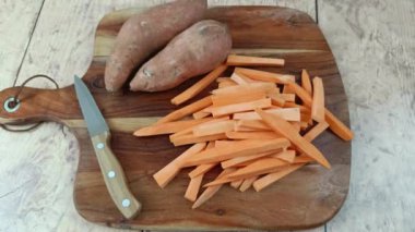 Kesme tahtasındaki çiğ patates kızartması yığını.