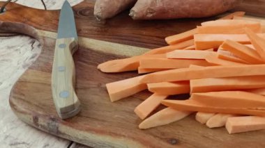 Kesme tahtasındaki çiğ patates kızartması yığını.