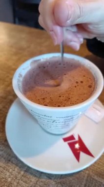 Sıcak çikolatayı bardağa karıştıran kişi.