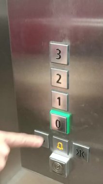Kadının eli asansörün düğmesine basıyor.