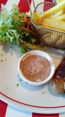 andouillette, hardal sosu ve tabakta patates kızartması.