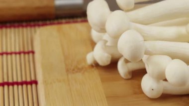 Birkaç çiğ enoki mantarı, yakın plan, bir tabakta.