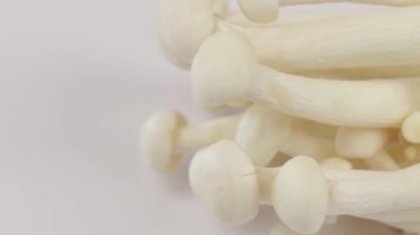 Birkaç çiğ enoki mantarı, yakın plan, beyaz arka planda izole edilmiş.