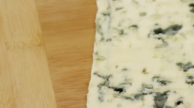 Bir dilim Rokfor peyniri, yakın plan, kesim tahtasında.