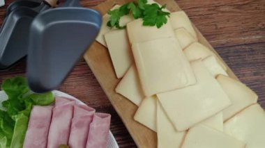 Masada raclette peyniri ve bir tabak şarküteri var.
