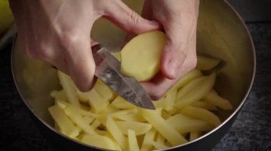Patates kızartması yapmak için patates kesen biri.