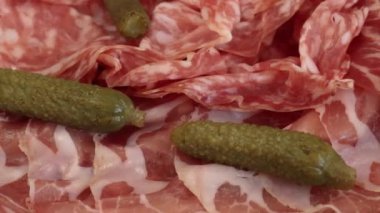 Bir tabak şarküteri ve raclette peyniri, yakın plan, masanın üstünde.