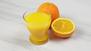 Bir bardak portakal suyu ve taze portakallar.