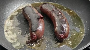İki siyah puding, bir tavada pişiyor.