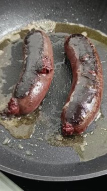 İki siyah puding, bir tavada pişiyor.