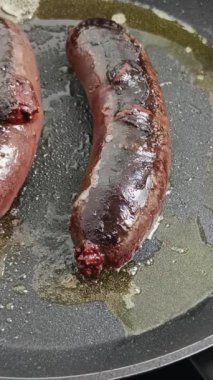 İki siyah puding, bir tavada pişiyor.