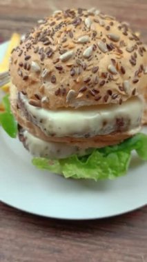 Bir tabakta duble burger ve patates kızartması, yakın plan.