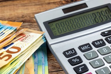 Bir tomar banknot ve hesap makinesi, yakın plan.