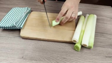 Kesme tahtasında pırasa kesen birinin yakın çekimi.