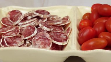 Dilimlenmiş sosis ve kiraz domatesli meze tabağı.
