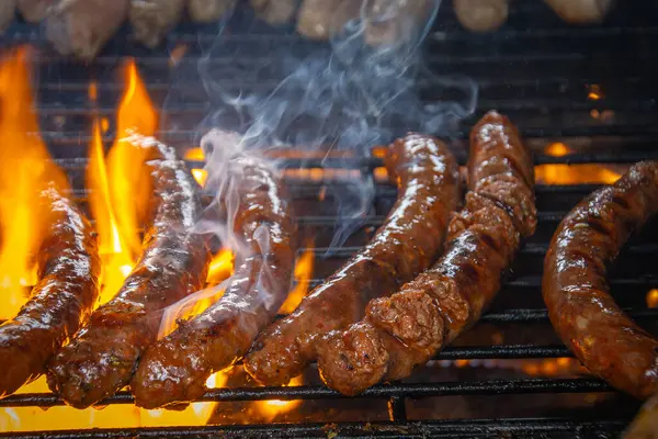 Merguez barbekü ızgarasında yemek pişiriyor, yağlar alevleri körüklüyor..