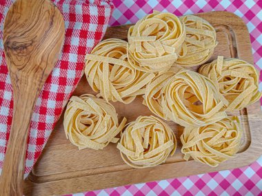 Kesme tahtasındaki çiğ tagliatelle makarnası