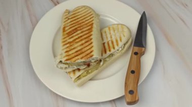 Panini sandviçi tabakta ikiye bölünmüş.