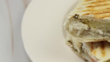 Panini sandviçi tabakta ikiye bölünmüş.