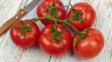 Domatesler sarmaşıkta, yakın planda, ahşap bir masada.