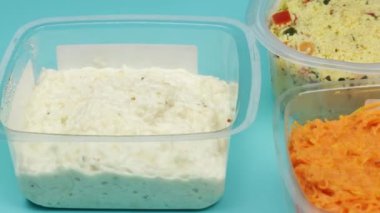 Endüstriyel çiğ sebze konserveleri: rendelenmiş kereviz, tabbouleh ve rendelenmiş havuç. Mavi bir arkaplanda izole edilmiş