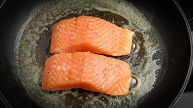 Tavada pişen somon parçaları.