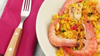 Bir tabak paella, ahşap bir masanın üstünde.