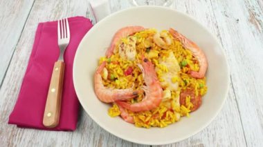 Bir tabak paella, ahşap bir masanın üstünde.