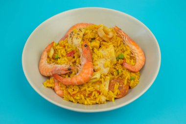 Bir tabak paella, üst görünüm, yakın plan, mavi arkaplanda izole edilmiş.