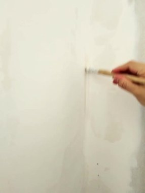 Boya fırçasıyla duvar boyayan birinin yakın çekimi.