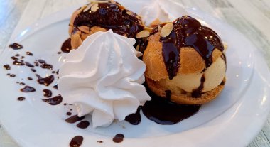 Krem şantili bir tabak çikolatalı profiterol