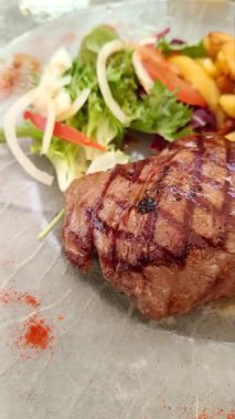 Lezzetli ızgara biftek, patates ve salata.